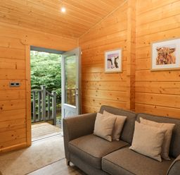A snug area with a sofa and door leading outside at Oak Lodge Pennington near Ulverston