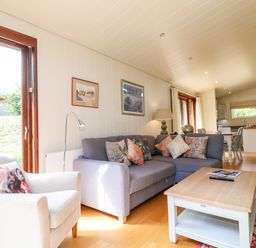 A living room with a gray sofa and an armchair with cushions and a wooden coffee table at Tickencote in Exton Rutland
