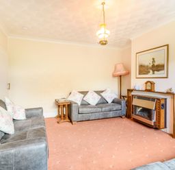 A living room with two sofas floral cushions a fireplace a painting and a floor lamp at The Perks in Scarborough