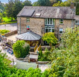A stone farmhouse with solar panels patio furniture and a garden at Eden Mill Millers Beck in Kendal