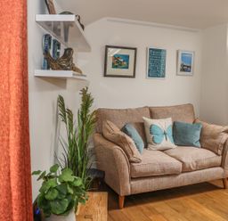 A sofa with cushions and framed pictures on the wall in a living room at The Compass in Swanage