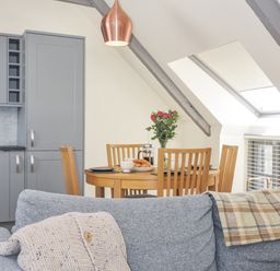 A kitchen with a dining table and flowers at Beach Retreat in Looe