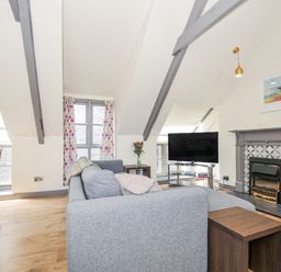 A living room with a couch and television at Beach Retreat in Looe