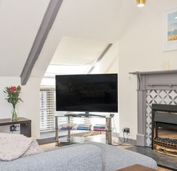 A living room with a television and sofa at Beach Retreat Looe