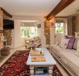 A living room with a sofa, coffee table, and fireplace at Puffitts Cottage in Bourton-on-the-Water