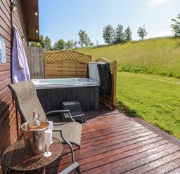An outdoor patio with a hot tub and seating area at 16 Badgers Retreat in Richmond