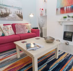 A living room with a pink sofa and coffee table at Beachcomber in Marazion