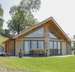 A wooden cabin with outdoor dining table and lounge chairs on a lawn at Shepherd's Rest in Montgomery