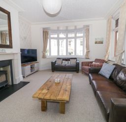 A living room with two leather sofas an armchair a wooden coffee table a fireplace and a television at 20 Ulwell Road in Swanage