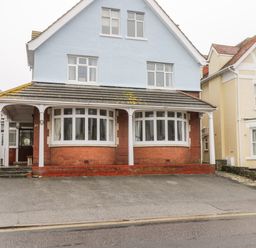 A detached house with a blue upper floor and brick lower floor featuring bay windows and a driveway at 20 Ulwell Road in Swanage