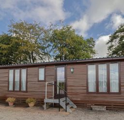 A wooden cabin with steps and windows at The Cabin at East Hill Pride Four Elms Hill Nr. Sidmouth