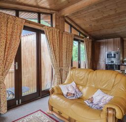 A living room with a yellow sofa and dining area at The Cabin at East Hill Pride Four Elms Hill Nr. Sidmouth