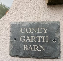 A stone plaque with the name 'Coney Garth Barn' at Coney Garth Barn in Beckermet