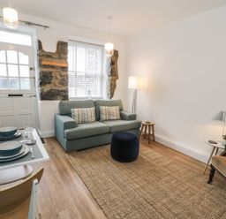 A living room with a sofa table set with plates and a bottle of wine and a chair at Llys Madoc in Porthmadog