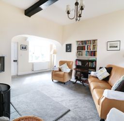 A living room with beige chairs a sofa bookshelf and a TV at Glebe House Wells