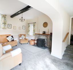 A living room with beige leather sofas a fireplace and floral curtains at Glebe House in Wells