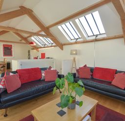 A living room with two black leather sofas and a wooden coffee table under skylights at Old Armoury Barn Ashburton