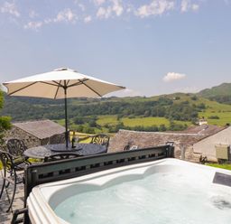 A hot tub and dining area with a view at Rose Cottage in Broughton-In-Furness