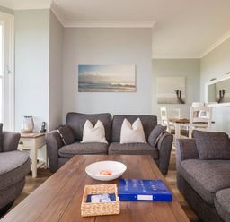 A living room with sofa, coffee table and dining area at Seashore House in Porth