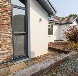An exterior view of a building with stone and white walls gravel ground and plants at Trenant View in Wadebridge