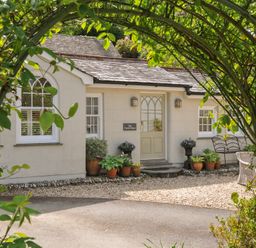 A house with potted plants and a sign at The Coach House at Pendower House Fowey