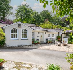 A cottage with potted plants and a gravel driveway at The Coach House at Pendower House Fowey
