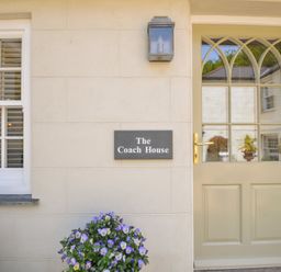 An entrance with a door and sign at The Coach House at Pendower House Fowey