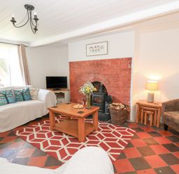 A living room with a sofa and armchair by a fireplace and a television at Pengraig near Tregaron
