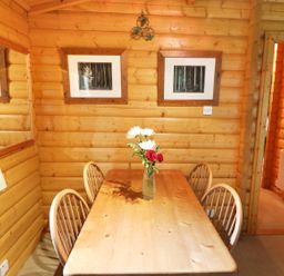 A wooden dining table with four chairs and a vase of flowers in a wooden panelled room at Lodge 8 in Louth