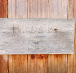 A wooden sign engraved with the word Brooke and a bird mounted on wooden wall panels at Brooke in Exton Rutland