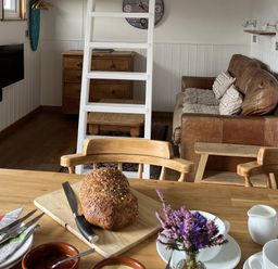 A living room with a dining table and a loaf of bread at Shepherds Cabin at Titterstone Clee Hill