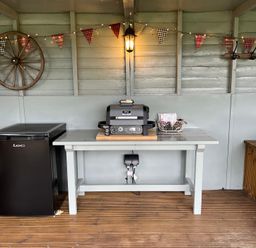 An outdoor shed with a grill and mini fridge at Shepherds Cabin at Titterstone Clee Hill
