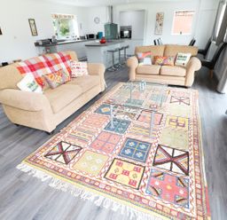 A living room with two beige sofas a glass coffee table and a colorful rug at Heron Lodge in Mavis Enderby near Spilsby