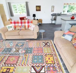A living room with two beige sofas a colorful patterned rug and a glass coffee table at Heron Lodge in Mavis Enderby near Spilsby