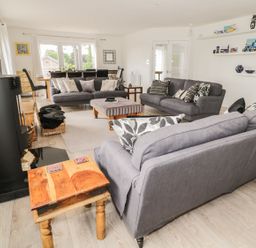 A living room with gray sofas wooden tables and a dining area at Manor House in Warkworth