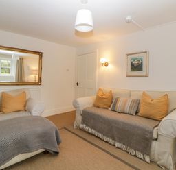 A living room with two sofas with cushions and throws a large mirror on the wall a wall lamp and a framed picture at Crannacombe Farmhouse in Loddiswell