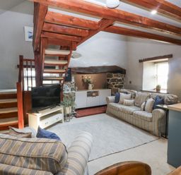 A living room with a staircase and television at Cegin Foch in Chwilog