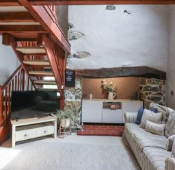 A living room with a staircase and a television at Cegin Foch in Chwilog