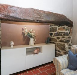 A living room with a stone wall and wooden beam at Cegin Foch in Chwilog