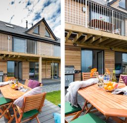 An outdoor wooden dining table with chairs cushions flowers fruit and a magazine on a deck outside a wooden house with balcony and barbecue at Godrevy in St Ives