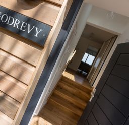 An open black door leading to a hallway with wooden floor and stairs at Godrevy in St Ives