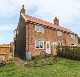 A brick two-story house with white doors and windows and a front garden at 2 Hillside Cottages Felixstowe Suffolk