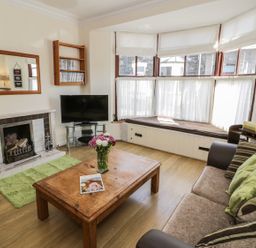 A living room with a fireplace a wooden coffee table a sofa and a bay window seat at Chwech in Menai Bridge