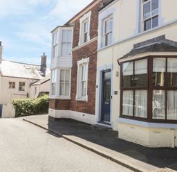 A street view of brick and painted houses with windows and a door at Chwech in Menai Bridge