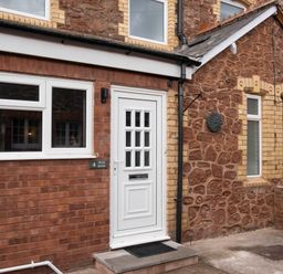 The exterior of a brick and stone house with a white door and windows at 4 High Bank