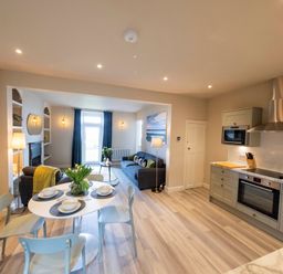 An open plan kitchen and living area with a dining table set with dishes and flowers at Harbour View Cottage in Watchet