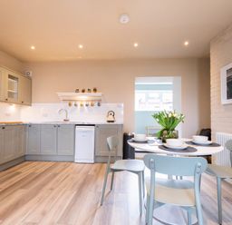 A kitchen and dining area with a round table set for four and gray cabinets at Harbour View Cottage in Watchet