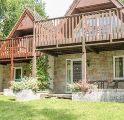 A two story stone house with a wooden balcony and outdoor seating area at Running Waters in Callington