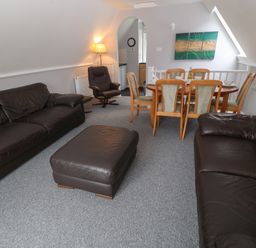 A living room with leather sofas a dining table and chairs and a lamp at Running Waters in Callington