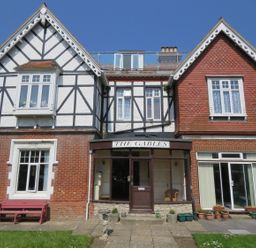 A brick and timber house with two gables and a central entrance labeled The Gables in Swanage
